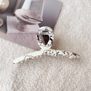 Close-up of cream large hair claw clip with black ink marble texture on soft fabric