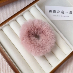 Detailed close-up of a pink plush faux fur hair scrunchie in a white jewelry box