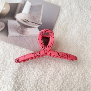 Detail of pink hair claw clip with black abstract lines on soft white fleece background