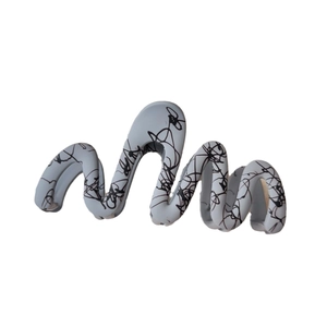 Artistic wave-shaped hair claw clip in matte grey-blue with black ink splatter patterns