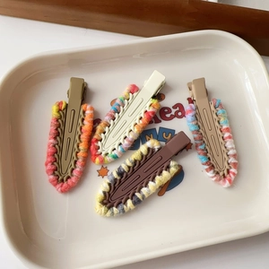 Set of four colorful wool woven hair clips with matte texture in a ceramic tray