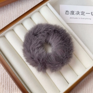 Detail of high-quality fluffy grey plush scrunchie displayed in a wooden jewelry box