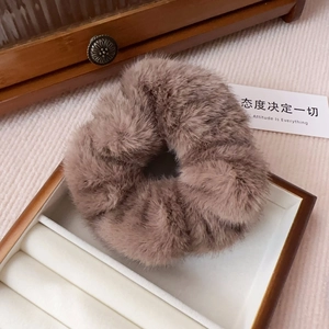 Close-up of deep coffee faux fur scrunchie on an ivory velvet jewelry box tray
