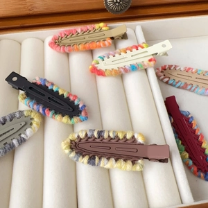 Detail of colorful knitted crochet hair clips in a white jewelry box with soft yarn texture