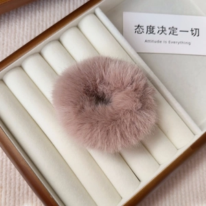 Detailed macro view of a fluffy pink faux fur scrunchie resting in a wood jewelry box