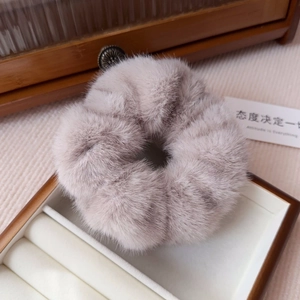 Close-up of grey-purple faux mink fur scrunchie on a premium wooden jewelry tray