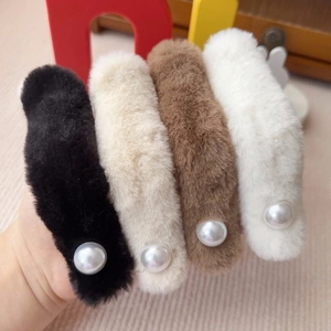 Nahaufnahme von vier Plüsch-Haarklammern mit Perlen in Schwarz, Beige, Braun und Weiß