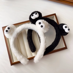 Detail showing soft black and white plush headbands with cute googly eyes on a tray