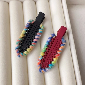 Detail of colorful woven wool yarn hair clips on white velvet jewelry storage box