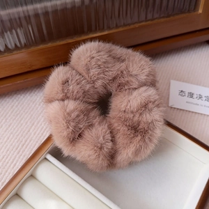 Detail shot of a plush faux mink hair scrunchie in khaki brown on a white display tray