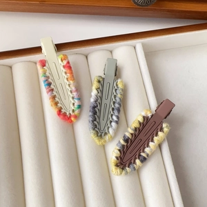 Detailed close-up of three knitted yarn duckbill hair clips in various contrast colors