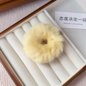 Close-up of bright yellow plush hair scrunchie in a premium jewelry display box