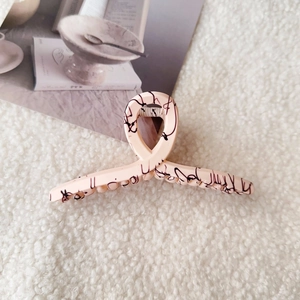 Macro shot of large pink marble shark hair clip on white faux fur and lifestyle magazine