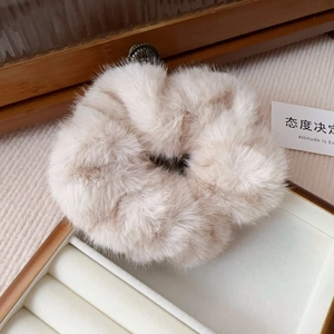 Detail of plush faux mink hair scrunchie in light beige with elegant vintage metal buckle