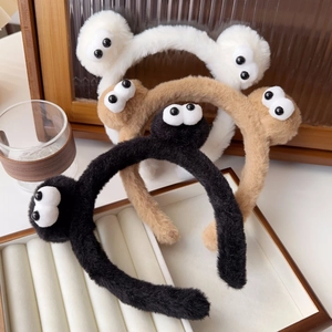 Detailed view of fluffy cartoon eyes headbands in black, brown, and white colors