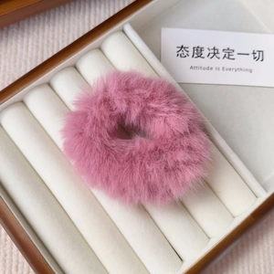 Close-up of a soft pink plush scrunchie showing fluffy faux fur texture in a wooden box