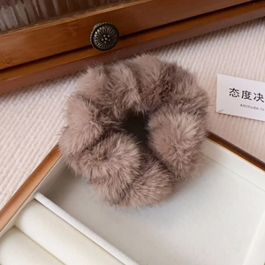 Detailed view of a soft brown faux mink fur scrunchie in an elegant jewelry storage box