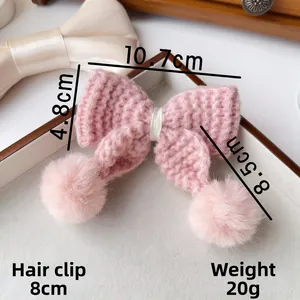 Détail de la pince à cheveux nœud tricoté rose avec pompons en peluche et base 8cm