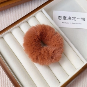 Close-up of caramel plush hair tie made of fluffy faux rabbit fur on wood jewelry box