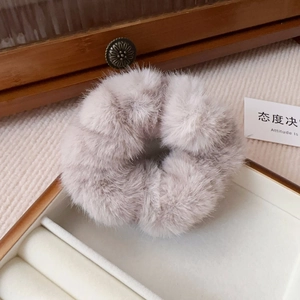 Detail view of grey faux mink fur scrunchie on soft fabric for autumn hairstyle