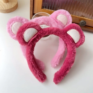 Close-up of soft plush bear ear headbands in pink and rose red for skincare routines