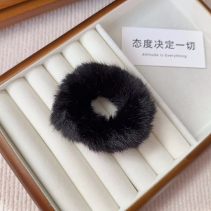 Close-up of a soft black plush scrunchie on a wooden jewelry box for winter