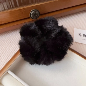 Detailed view of plush faux mink fur scrunchie resting on a vintage wooden jewelry box