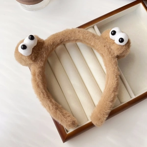 Close-up of fluffy brown plush headband with 3D cartoon eyes and soft furry texture