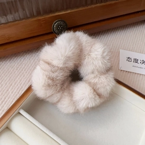 Close-up of beige plush faux mink hair scrunchie in a vintage wooden jewelry box