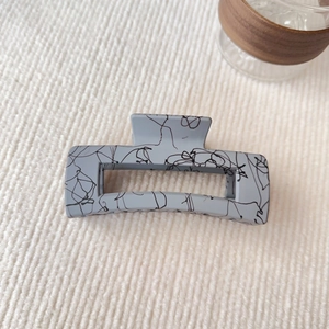 Vista macro di una grande pinza per capelli quadrata blu chiaro da 12,5 cm con motivi neri