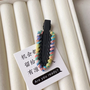 Close-up of a colorful hand-knitted wool hair clip on a premium white jewelry tray