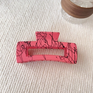 Dettaglio macro della molletta per capelli quadrata 12,5cm rosa opaco con macchie nere