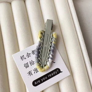 Close-up of contrast wool woven duckbill hair clip in grey and yellow on jewelry box
