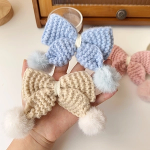 Détail des barrettes à cheveux en nœud tricoté main avec pompons en fourrure douce