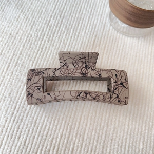 Dettaglio macro di un fermaglio per capelli rettangolare beige da 12,5cm con macchie nere