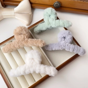 Detail view of four fluffy faux fur hair claws in beige, green, purple and white