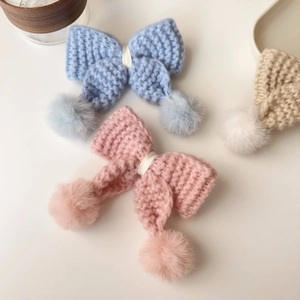 Trois barrettes nœuds en tricot avec pompons en fourrure en bleu, rose et beige