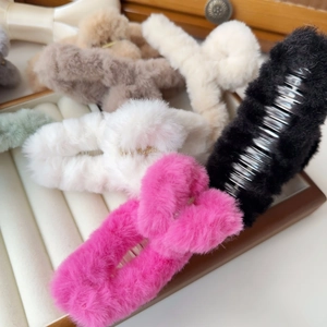 Macro shot of assorted colorful plush claw clips on a wooden jewelry display case