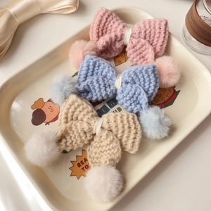 Détail macro de barrettes à cheveux nœud tricoté main avec pompons doux en trois couleurs