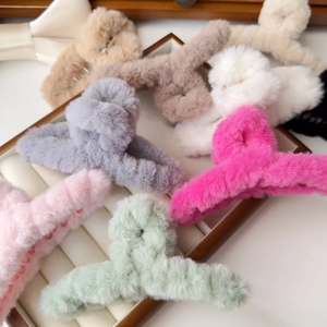 Detailed close-up of colorful plush faux fur hair claw clips on a soft wooden jewelry tray