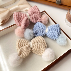 Vue détaillée de barrettes à nœuds tricotés main avec pompons en peluche douce