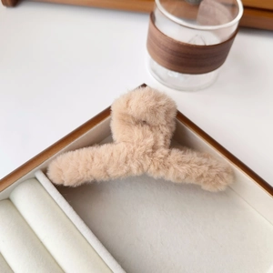 Detail of plush faux fur hair claw clip in beige on a soft aesthetic background