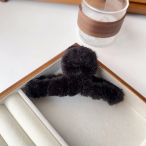 Detail of soft black plush hair claw clip displayed in an elegant wooden jewelry gift box
