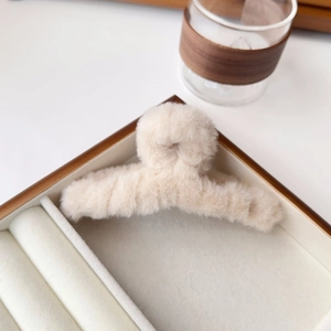 Detail of soft cream-colored plush claw clip showing fluffy faux fur texture for winter