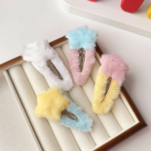 Détail de quatre pinces à cheveux étoiles en peluche colorées dans un coffret à bijoux