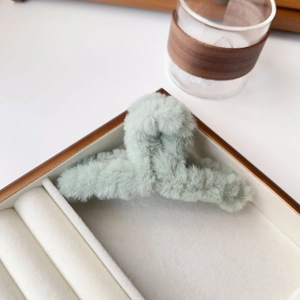 Detail of mint green plush hair claw clip with soft faux fur texture in a jewelry box