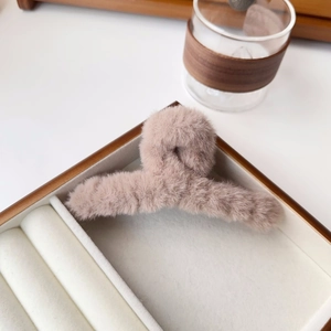Close-up of soft plush claw clip in dusty pink resting on a wooden jewelry box