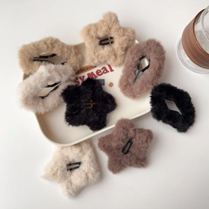 Dettaglio di fermagli per capelli in peluche a stella e ovali in colori neutri terra