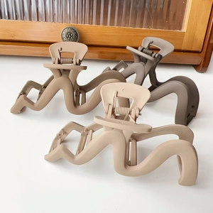 Three matte wave hair claws in dark coffee, khaki, and cream colors on white surface