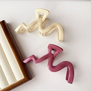 Close-up of wave-shaped large shark hair clips in cream white and morandi purple colors